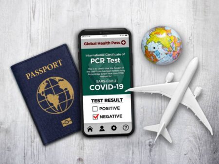 Fit to Fly PCR Test Result in a Smartphone and Passport Accompanied by a Miniature Airplane and Globe