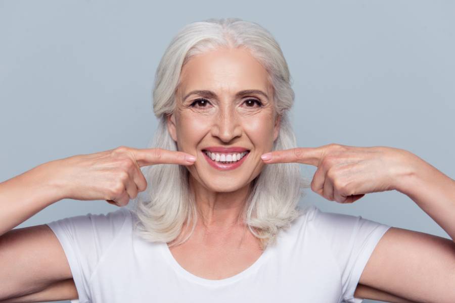 Happy Older Woman Pointing at Perfect Teeth