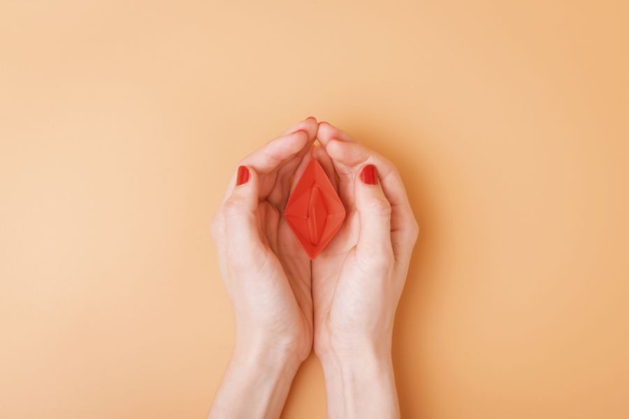 A Red Paper Boat Protectively Covered by a Woman's Hands